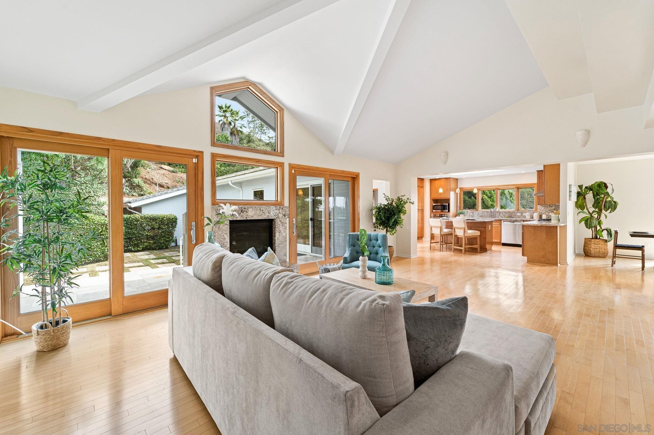 La Jolla Reimagined — vaulted living room with fireplace opening to kitchen